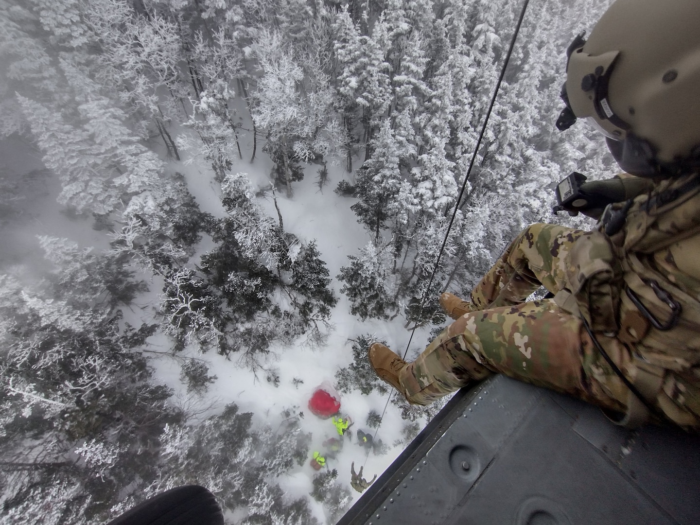 From a hover of 70 feet, Sgt. Daniel Bourque, a medevac crew member with the New Hampshire Army National Guard, lowers Sgt. 1st Class Ethan Major during a rescue operation Dec. 19, 2024, on Franconia Ridge.