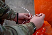 An Airman ties a sandbag.