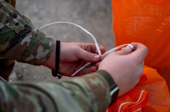 An Airman ties a sandbag.