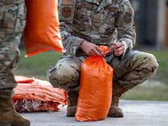 An Airman ties a sandbag.