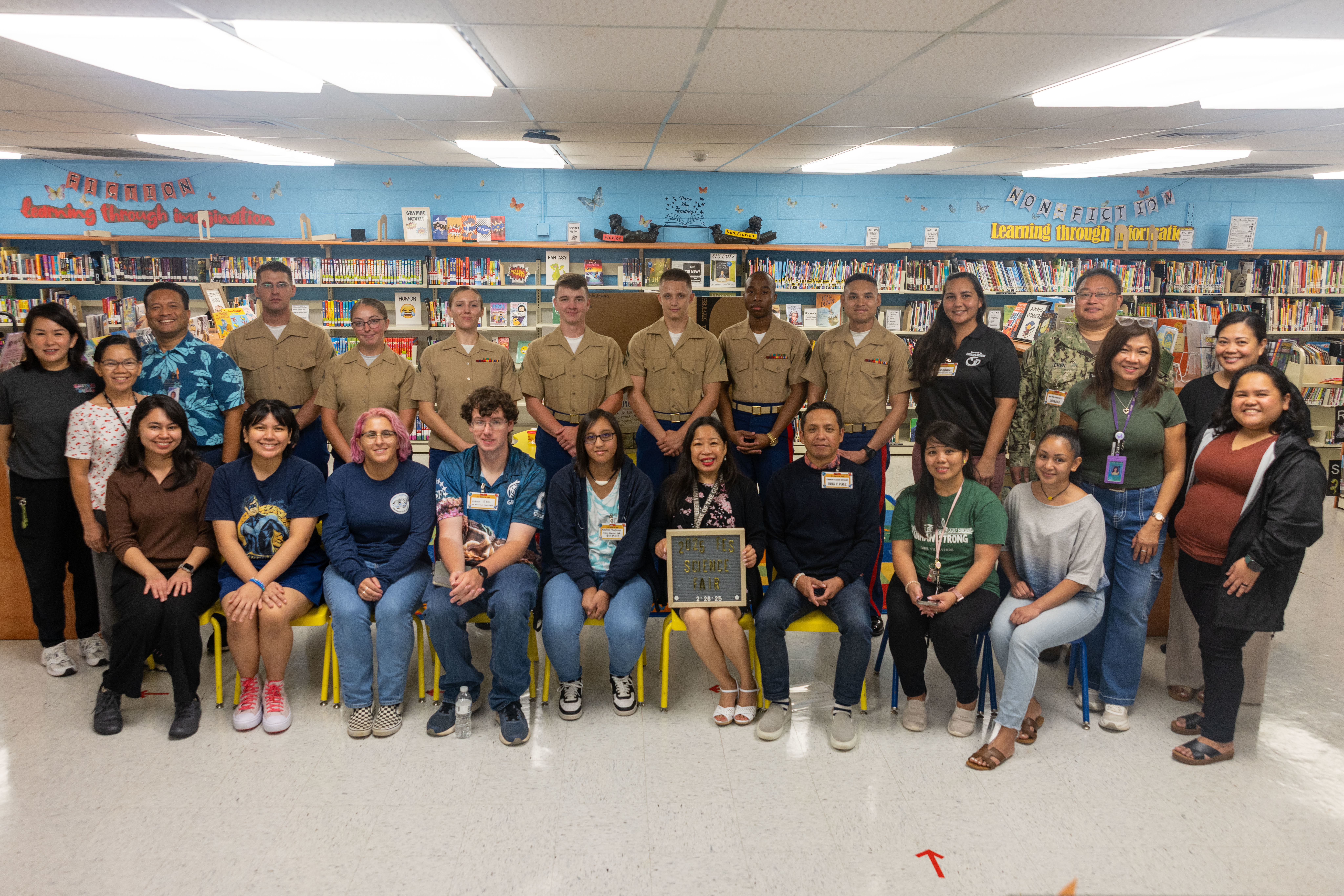 U.S. Marines and staff with Marine Corps Base Camp Blaz and 3rd Marine Logistics Group, Finegayan Elementary faculty and staff, and additional volunteer partners pose for a group photo post-science fair judging at Finegayan Elementary School, Dededo, Guam, Feb. 26, 2025. Marines and staff judged and interviewed students on their science fair projects, assisting in selecting the student projects that will proceed to represent the school at an island wide science fair. (U.S. Marine Corps photo by Chelsey Suarez-Pierce)