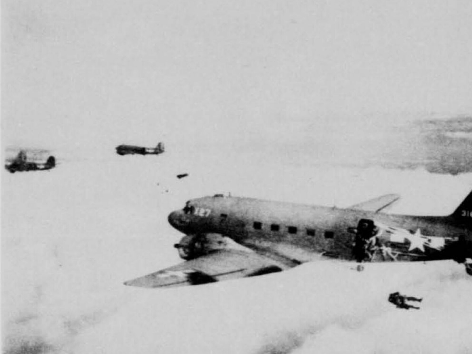 Courtesy photo depicts 511th Parachute Infantry Regiment paratroopers airdropping over Tagaytay Ridge, Feb. 3, 1945. The 317th Troop Carrier Group C-47 Skytrains airdropped the 11th Airborne Division in three groups over Tagaytay Ridge in support of the liberation of the Japanese-occupied capital, Manila. 80 years later, the same two units conducted airdrops over a different Indo-Pacific strategic area, the Arctic.  (Photo by Courtesy Photo)