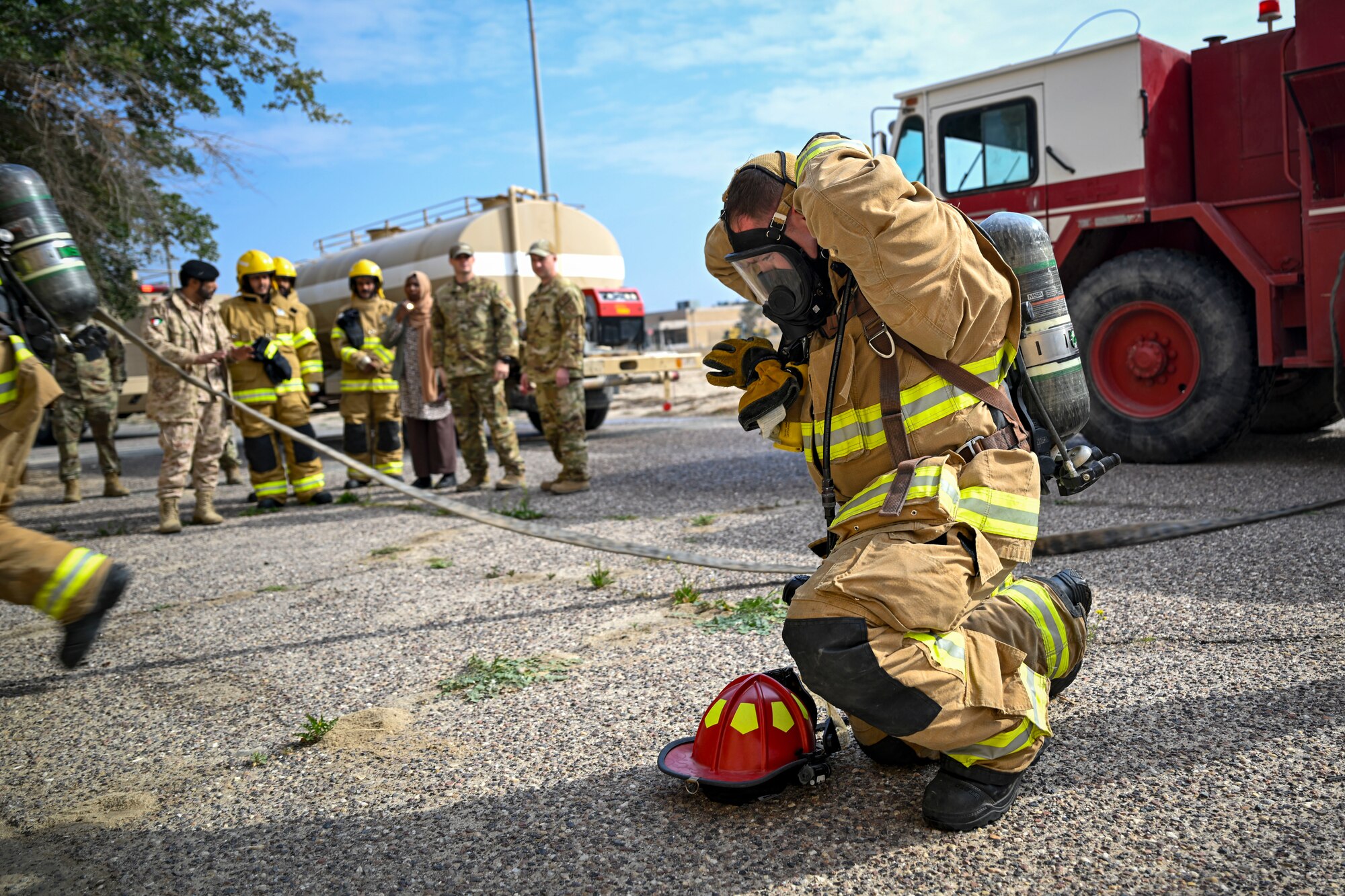 A firefighters kneels as he puts on his mask.