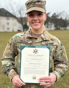 Army Spc. Maggie Wilson holds up her promotion certificate following her promotion to corporal March 10 on Daenner Kaserne in Kaiserslautern, Germany. Wilson graduated the Army’s Basic Leader Course March 7 and is set to reenlist for four more years March 13. That’s a lot in one week, said the human resources NCO at the 405th Army Field Support Brigade’s administration and human resources directorate (S-1). (U.S. Army courtesy photo)