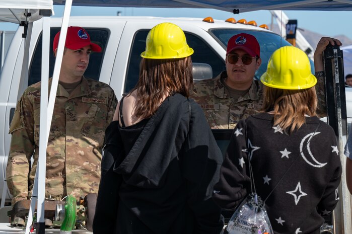Two Airmen speak to two local students during Construction Career Day.