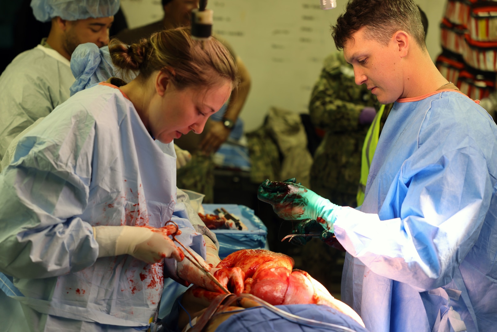 Cmdr. Rebecca Rieger (left) and Cmdr. Landon King (right), with the Expeditionary Medical Facility (EMF) 150-Alpha surgical team, perform surgery on a live actor wearing a surgical “cut suit” simulating an iliac artery and bowel injury, and a right leg amputation, sustained from an improvised explosive devise (IED) explosion, during an EMF training and Operational Readiness Evaluation (ORE) at the Naval Expeditionary Medicine Warfighter Development Center (NEMWDC), Camp Pendleton, Calif., Feb. 15-28. "The EMF course provided real-world training,” said Capt. Kenneth Basford, EMF 150 Alpha commanding officer.  “This evolution better equipped our Sailors with the ability to perform under pressure through various scenarios. Additionally, this training helped build camaraderie, unit cohesion, unity of effort, and overall efficient teamwork for EMF Alpha."