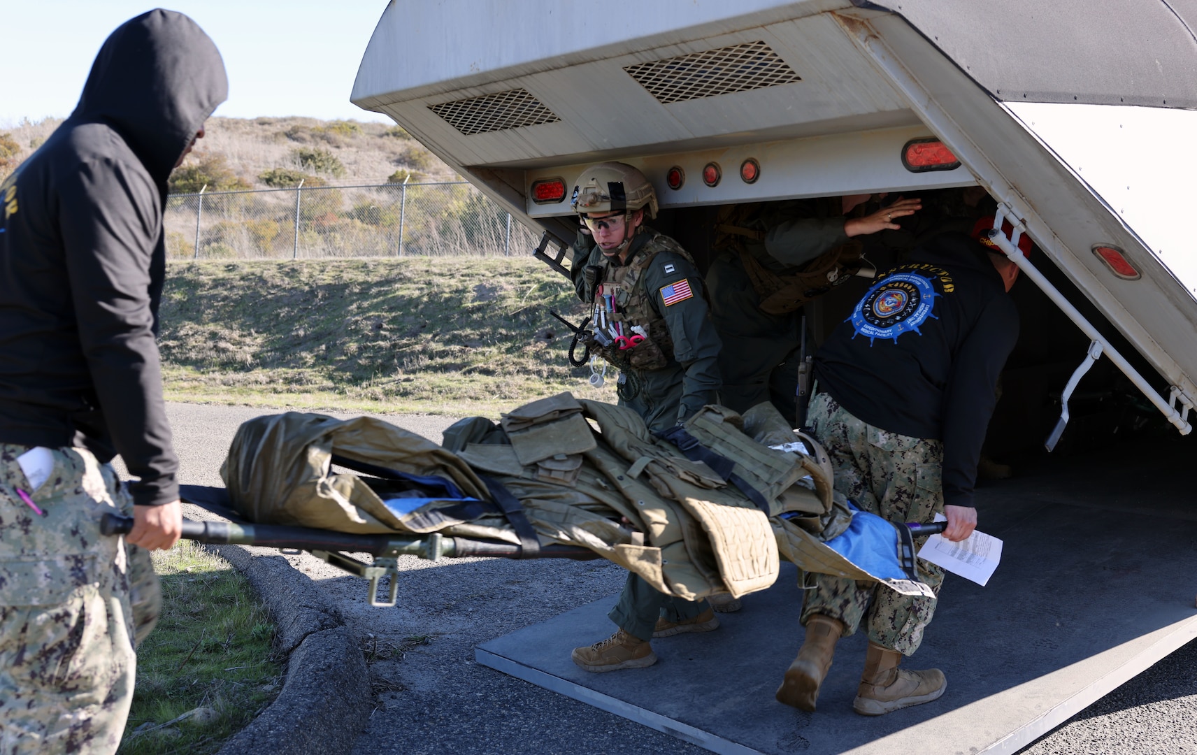 Lt. Stephanie Ryan, a Role 2 En-Route Care System (ERCS) flight nurse with ERCS 11-15 San Diego, receives a patient being loaded into a simulated aircraft for transport to a Role 3 facility during the Expeditionary Medical Facility (EMF) 150-Alpha training and Operational Readiness Evaluation (ORE) conducted at Naval Expeditionary Medicine Warfighter Development Center (NEMWDC), Camp Pendleton, Calif., Feb. 15-28.   The training scenarios incorporated the ERCS platform, enhancing the realism the expeditionary medicine (EXMED) systems may experience during operations. The ERCS is a two-person team that provides personnel, equipment, and consumables for uninterrupted continuation of patient care during movement.