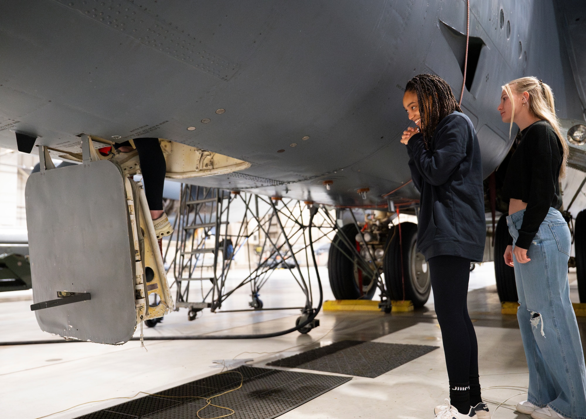 Students from the Minot State University Track & Field Team watch a fellow student climb into a B-52H Stratofortress at Minot Air Force Base, North Dakota, March 4, 2025. The tour provided the opportunity to educate students and coaches about the 5th Bomb Wing. (U.S. Air Force photo by Senior Airman Kendra A. Ransum)