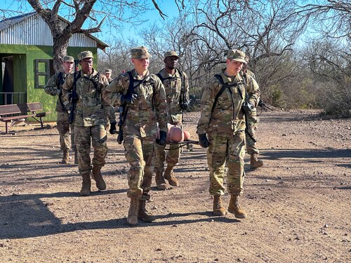 Four trainees carry a medical litter with a mannequin