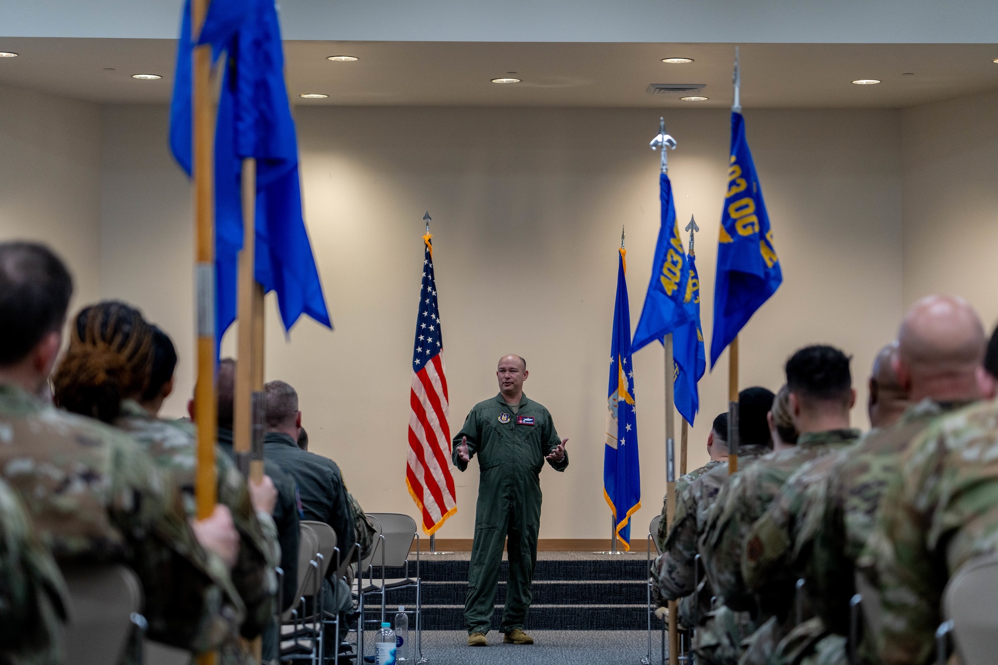Colonel addressing wing Airmen in an auditorium