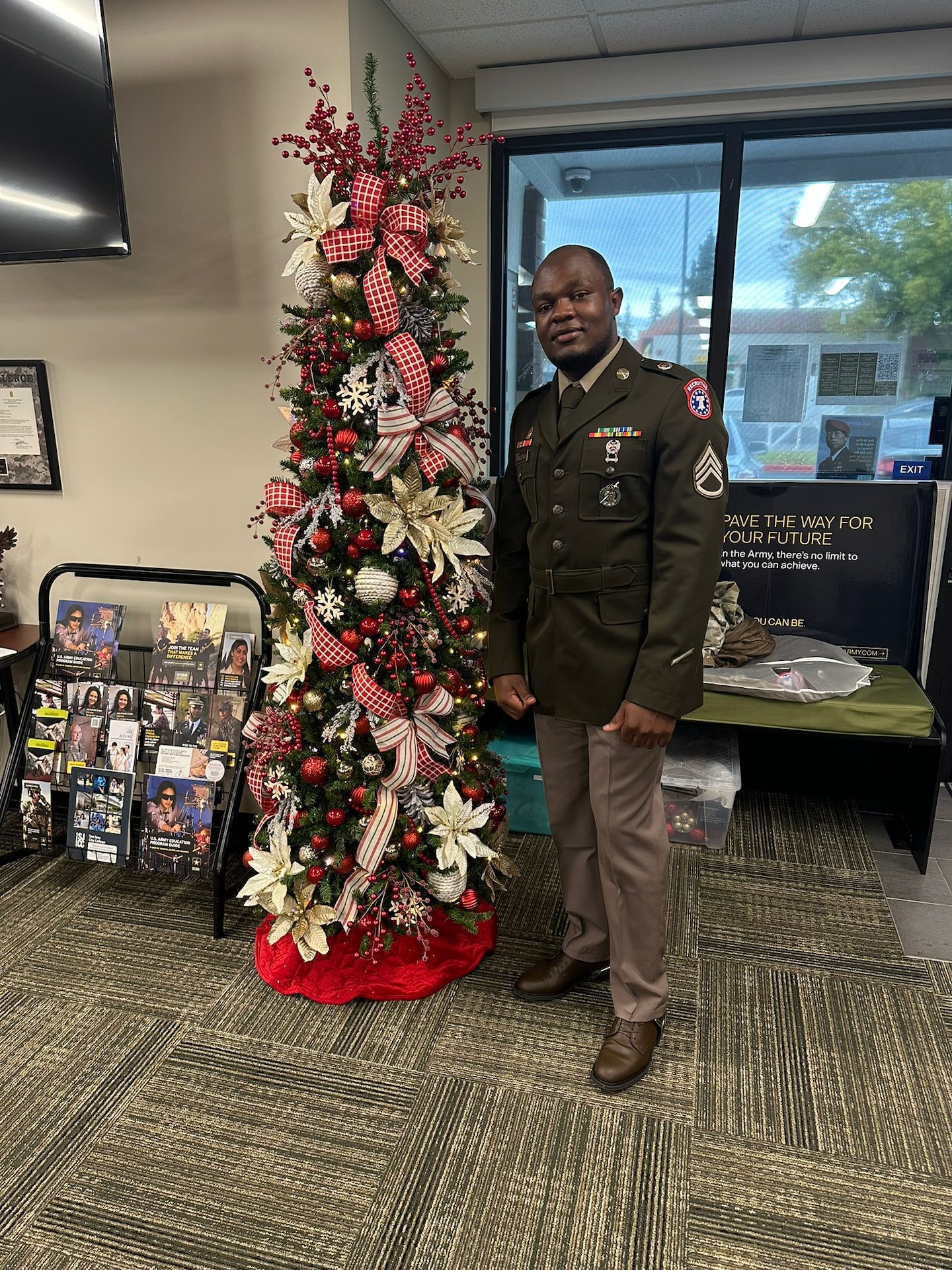 U.S. Army Soldier in uniform poses with office Christmas Tree