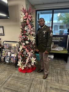 U.S. Army Soldier in uniform poses with office Christmas Tree