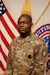 Male U.S. Army Soldier poses in uniform in front of the American flag and USAREC flag