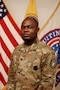 Male U.S. Army Soldier poses in uniform in front of the American flag and USAREC flag