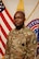 Male U.S. Army Soldier poses in uniform in front of the American flag and USAREC flag