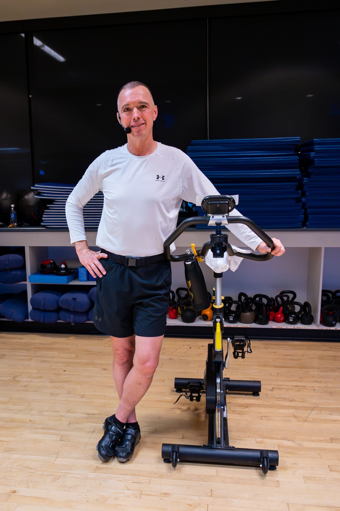 Lt. Col. Hale standing next to spin bike prior to leading group spin class.
