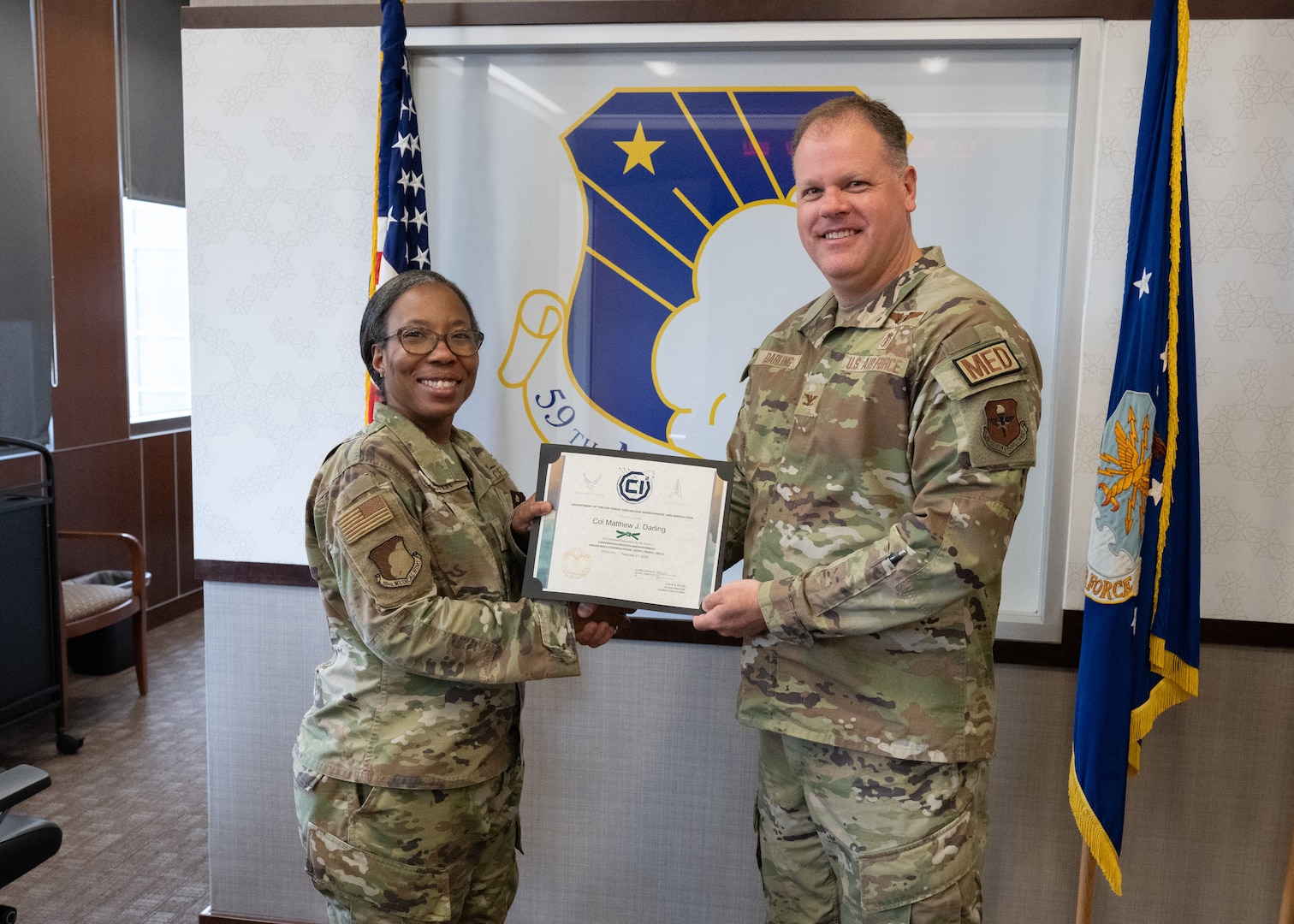 U.S. Air Force Brig. Gen. Gwendolyn Foster, and Col. Matthew Darling pose for a photo after Darling received his Continuous Improvement Green Belt certification at Wilford Hall Ambulatory Surgical Center, Joint Base San Antonio-Lackland, Texas, March 7, 2025.