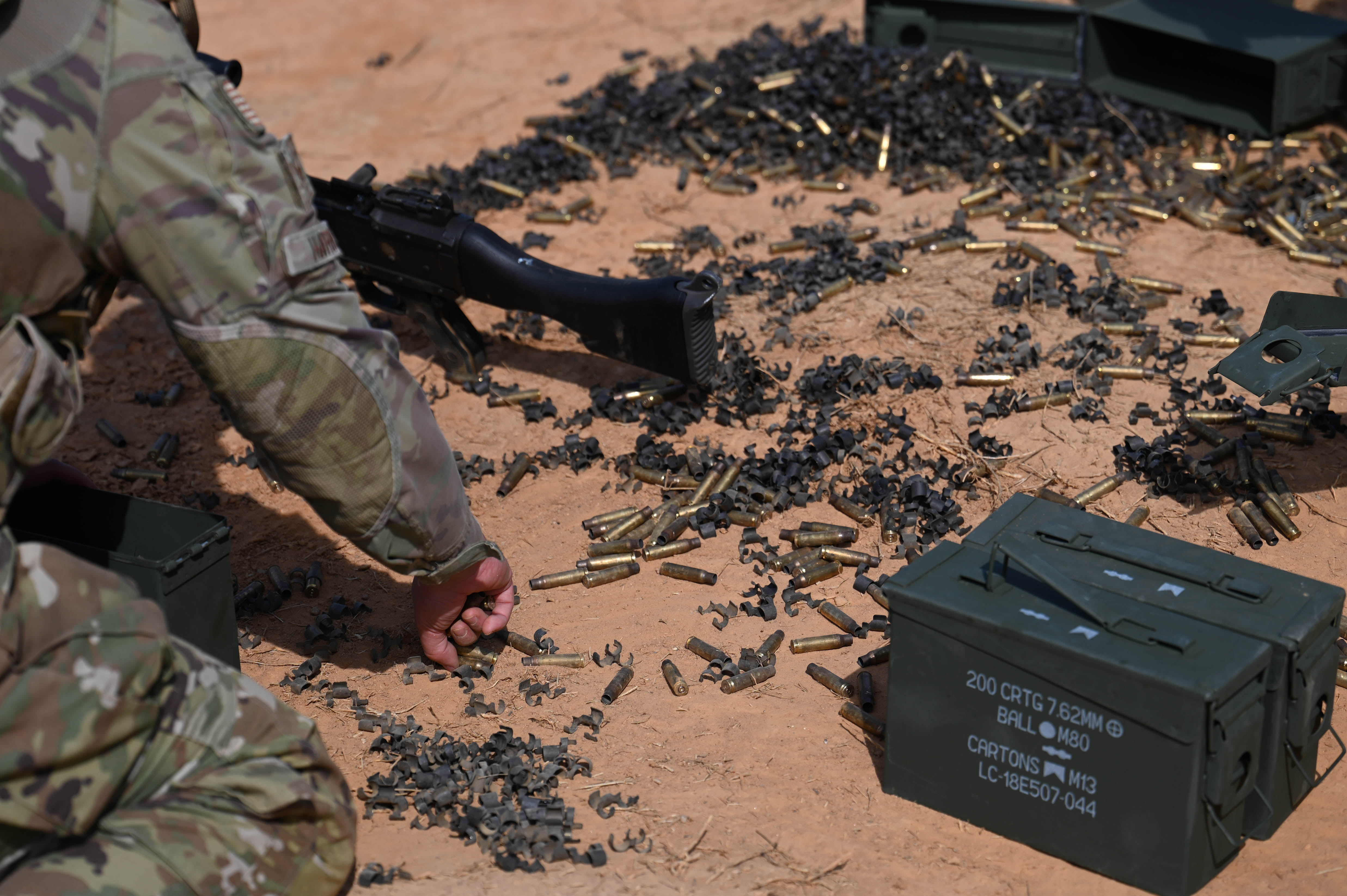 U.S. Air Force Senior Airman Jessica Hardin, security forces specialist with the 11th Security Forces Squadron, picks up bullet shells and disintegrating ammunition belts after heavy weapons training at Marine Corps Base Quantico, Va., March 4, 2025. The training prepared security forces members for Mission Focused Rehearsal Training at Fort Bliss, Texas, where they will be challenged with a realistic representation of a deployed environment. (U.S. Air Force Airman 1st Class Geneva Nguyen)