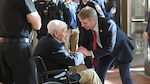 A man greets a man in a wheelchair