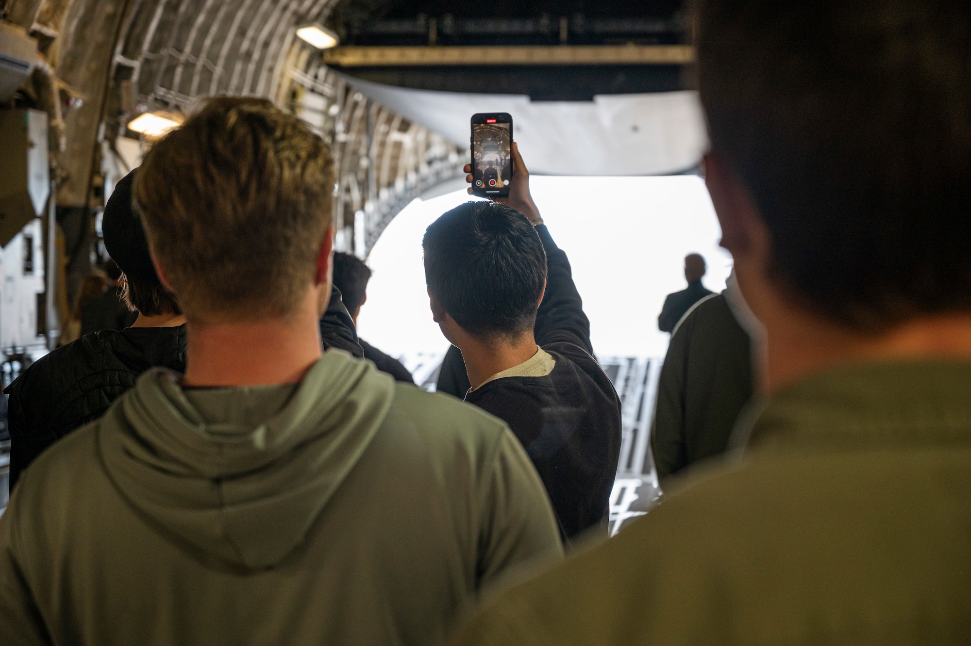Students from the Big Bend Community College aviation program watch and film the ramp of a 62d Airlift Wing C-17 Globemaster III open after a McChord Flight Safety Office midair collision avoidance brief in Moses Lake, Washington, March 7, 2025.