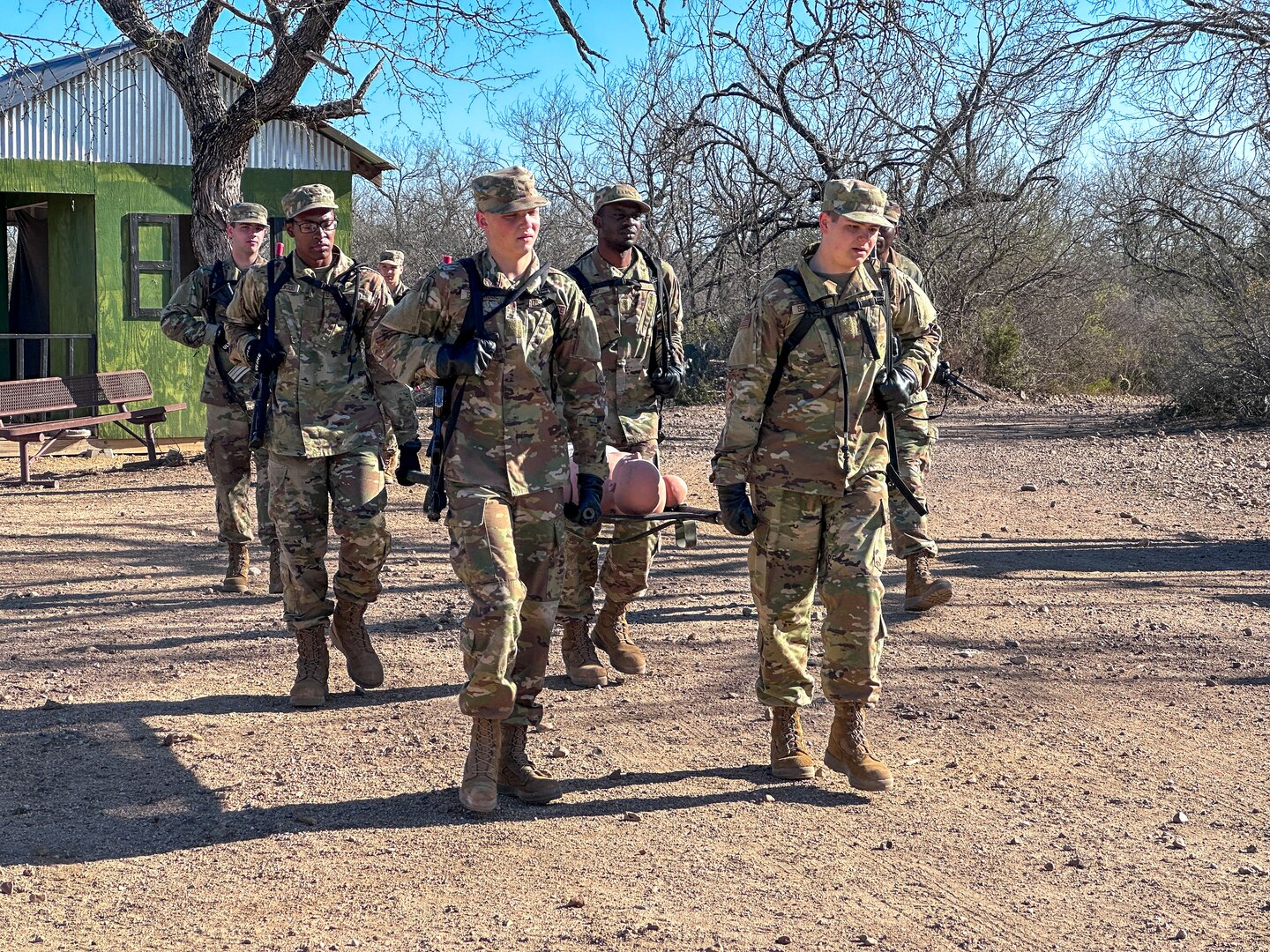 Four trainees carry a medical litter with a mannequin