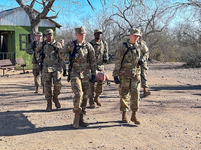 Four trainees carry a medical litter with a mannequin