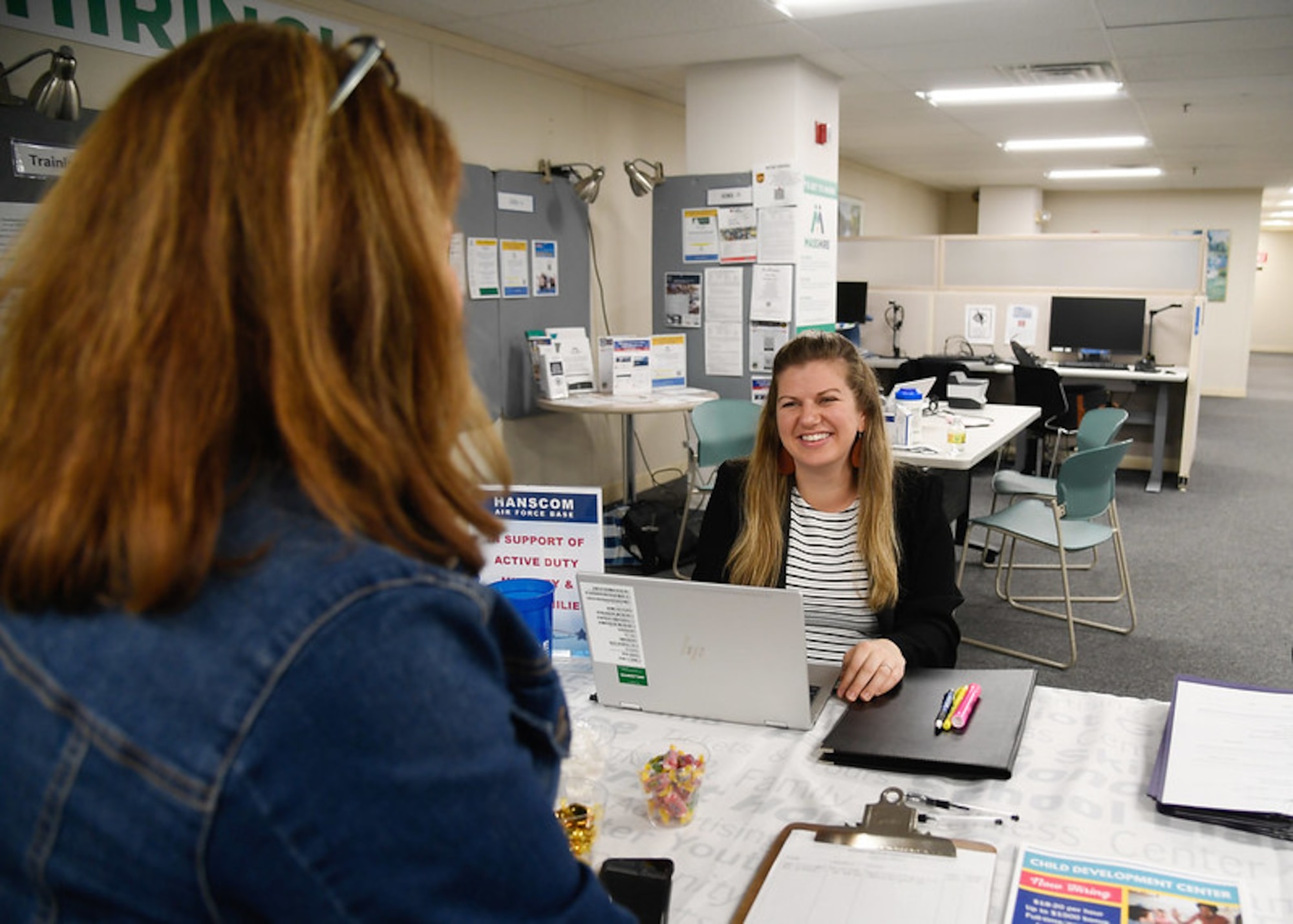 Woman smiles behind computer.