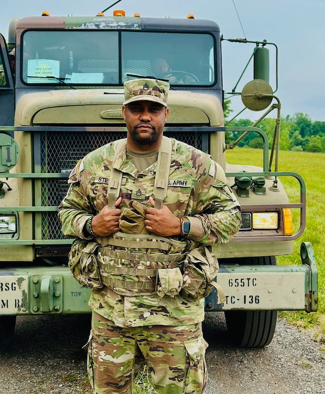 Man in army uniform standing in front of tactical vehicle