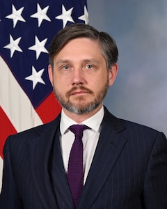 official portrait of Dr. Fritz in front of blue background and American flag behind to the left