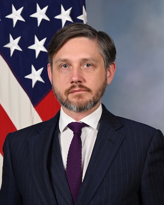 official portrait of Dr. Fritz in front of blue background and American flag behind to the left