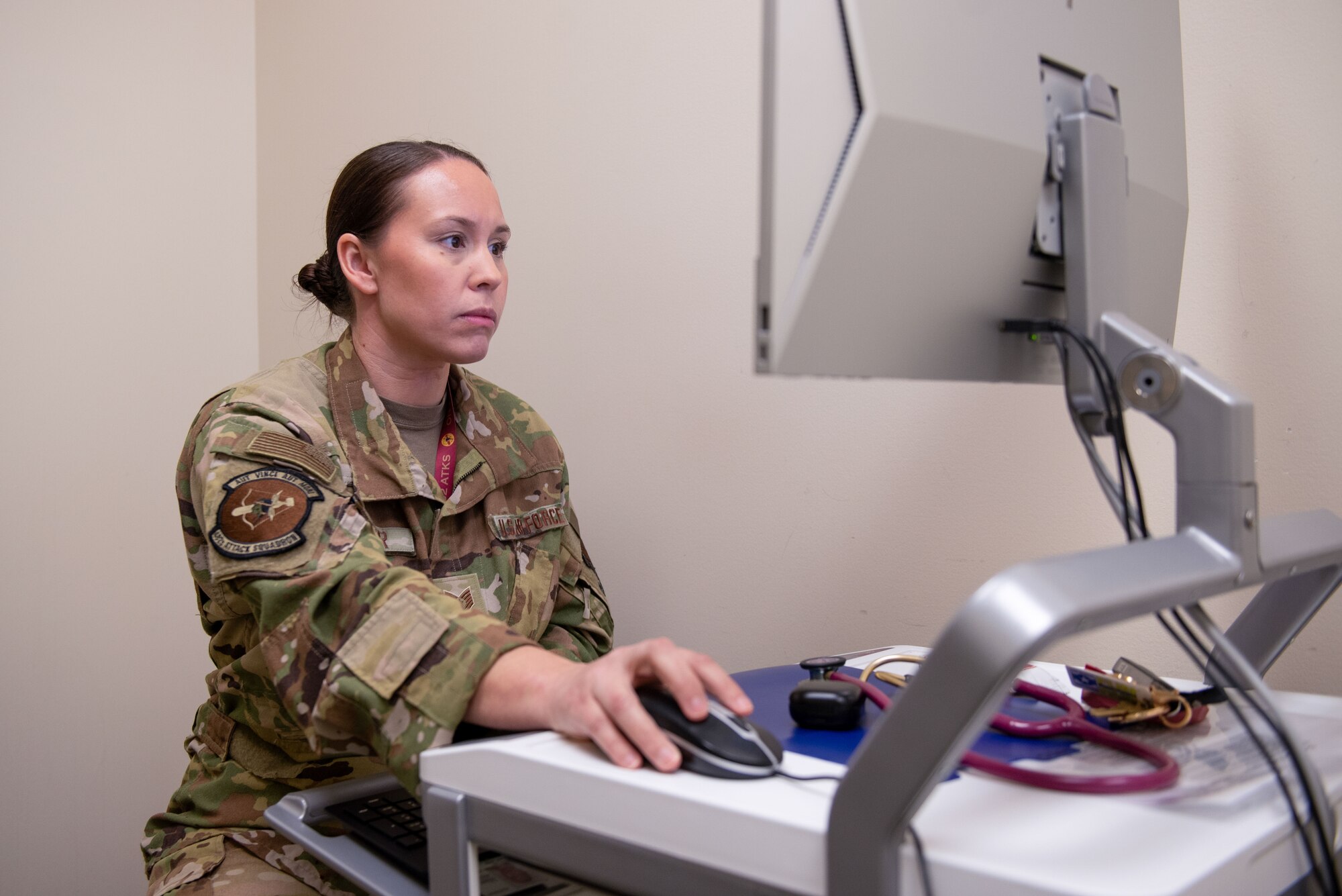 A woman in a military uniform works on a computer.