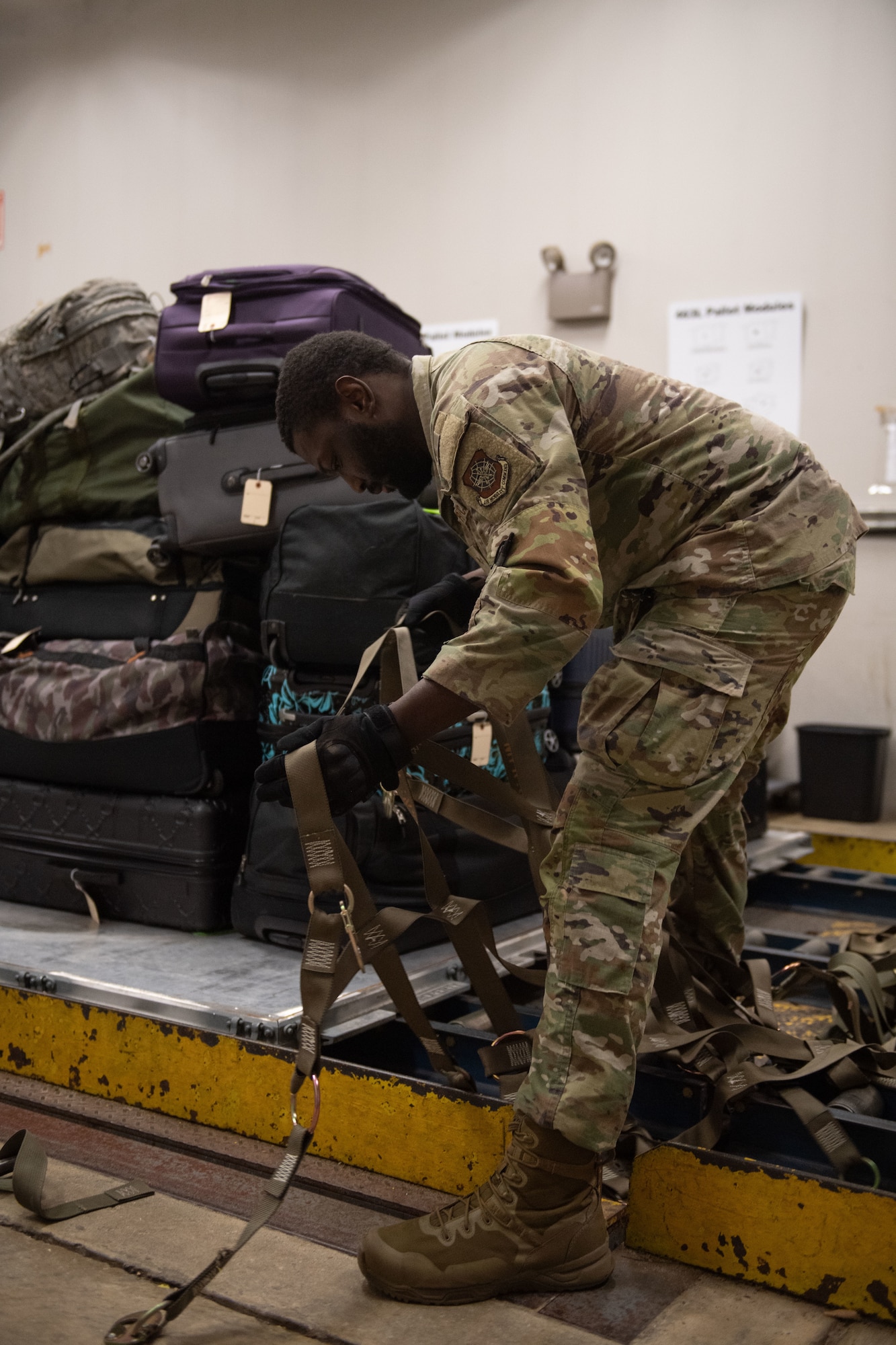 U.S. Air Force Senior Airman Jordan Williams, 436th Aerial Port Squadron Passenger Terminal passenger service representative, prepares to throw cargo netting over a baggage pallet at the Passenger Terminal at Dover Air Force Base, Delaware, Mar. 8, 2025. At the 436th APS Passenger Terminal, active duty, reserve, guard, disabled veterans, retirees and their dependents can travel overseas on the C-5M Super Galaxy and the C-17 Globemaster III, at a low cost. (U.S. Air Force photo by Airman 1st Class Liberty Matthews)