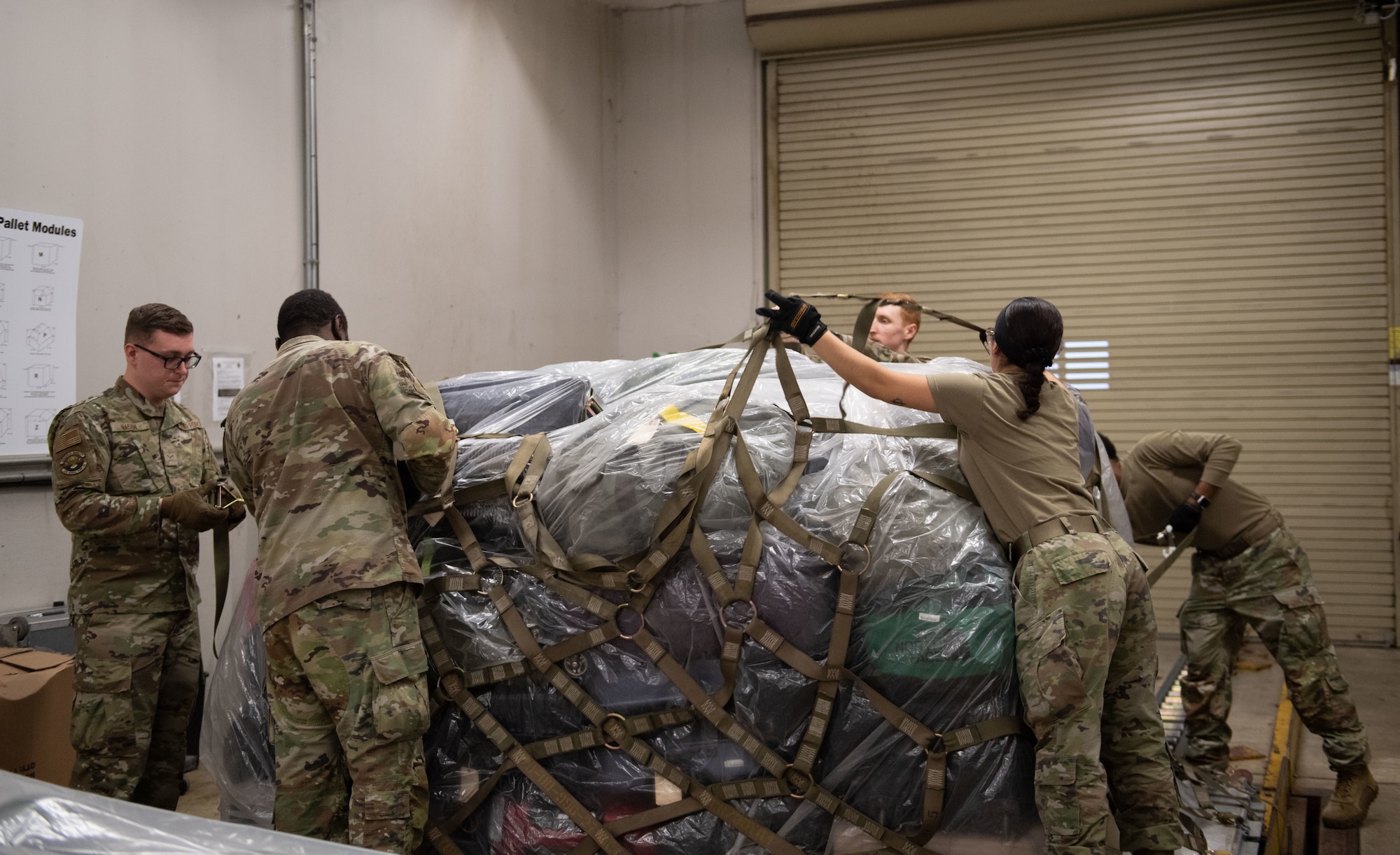 Airmen from the 436th Aerial Port Squadron Passenger Terminal throw cargo netting over a baggage pallet at Dover Air Force Base, Delaware, March 8, 2025. At the 436th APS Passenger Terminal, active duty, reserve, guard, disabled veterans, retirees and their dependents can travel overseas on the C-5M Super Galaxy and the C-17 Globemaster III, at a low cost. (U.S. Air Force photo by Airman 1st Class Liberty Matthews)