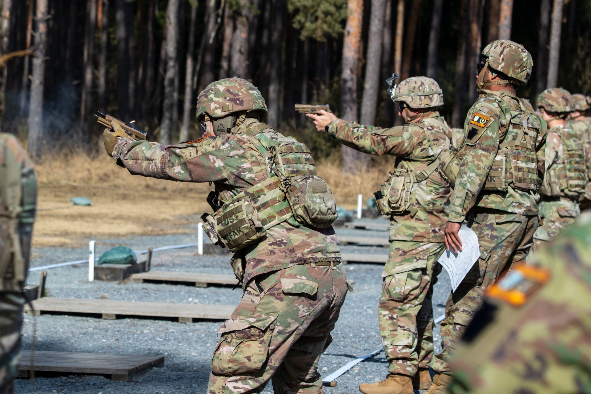 Firers stand and engage their targets during a pistol competition at Grafenwoehr Training Area, March 9, 2025. The competition consisted of two events: a 30-yard slow fire match and a four-stage excellence-in-competition match whereby 10 percent of the top eligible competitors could earn career points toward the Distinguished Pistol Shot Badge. U.S. Soldiers with the 2nd Cavalry Regiment and the 7th Army Training Command joined the 56th Stryker Brigade Combat Team at the pistol competition, thus contributing to camaraderie among units, the opportunity to earn career points toward the Distinguished Pistol Shot Badge and improved readiness and lethality in marksmanship training. (U.S. Army National Guard photo by Capt. Leanne Demboski)