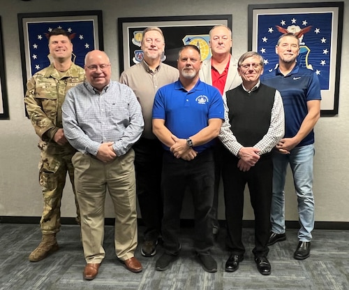 seven team members pose against a wall.