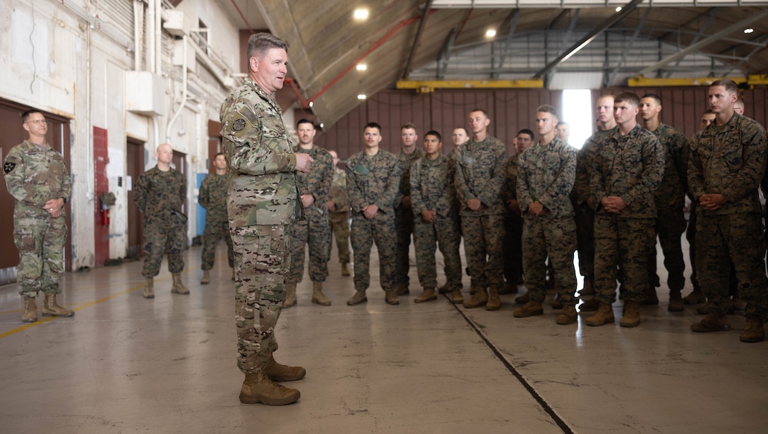 A soldier speaks to dozens of Marines.