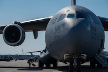 An Airman secures a C-17 Globemaster III cargo aircraft with aircraft tire chocks