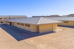 Several buildings, both single story and two-story, sit near each other in a large dirt patch.