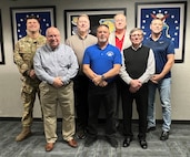 seven team members pose against a wall.