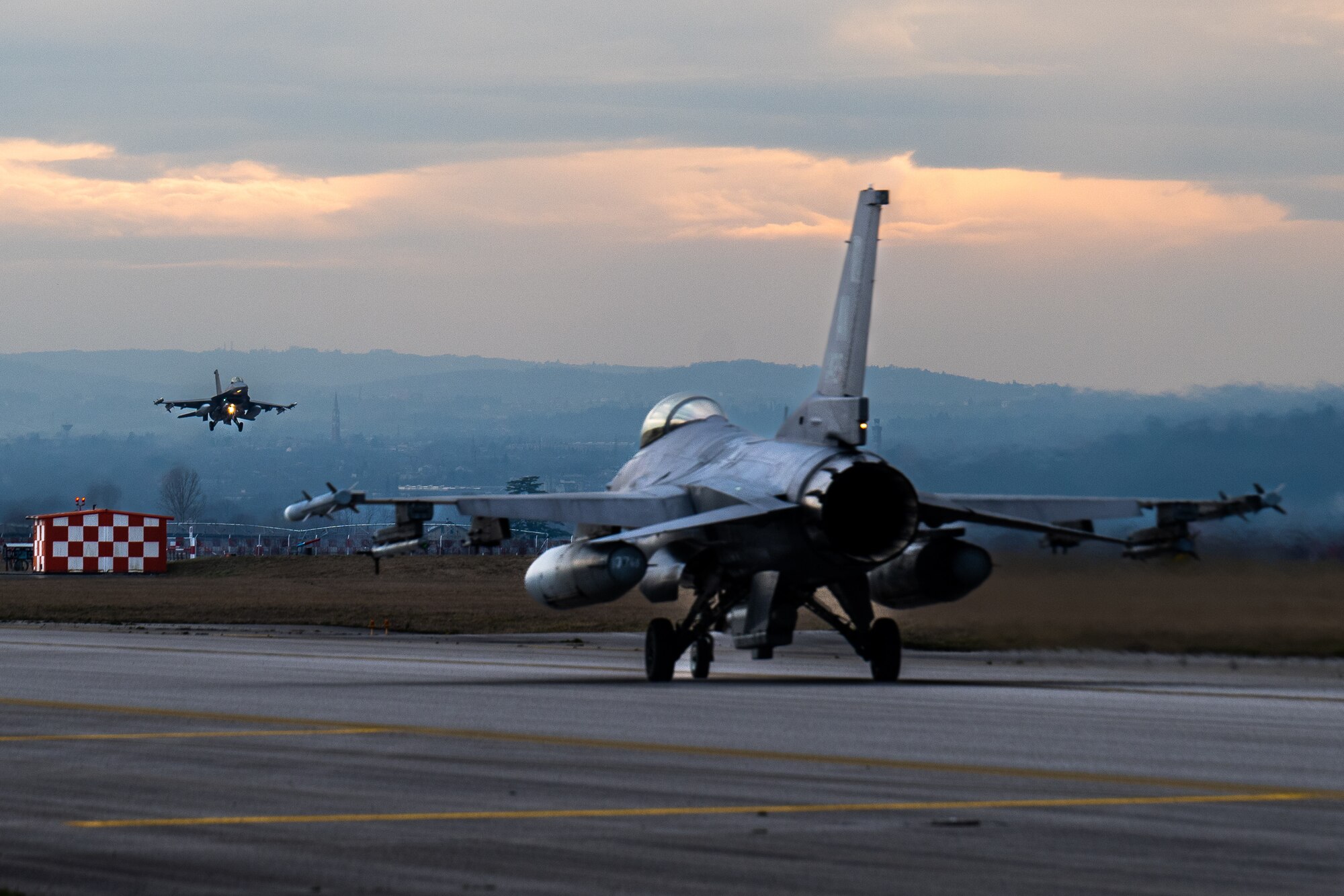 A jet prepares to land and another jet taxis down the runway.