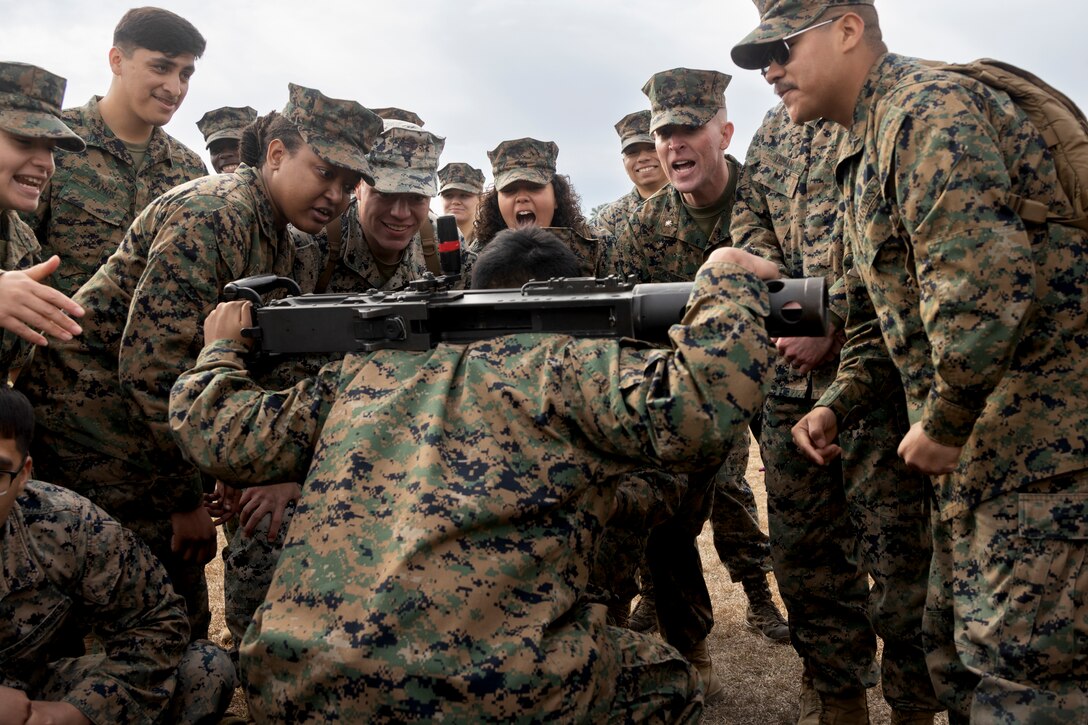 U.S. Marines with 2nd Marine Logistics Group, cheer on a fellow Marine participating in a squat competition as part of the H&S Bn Field Competition at Camp Johnson, North Carolina, March 7, 2025. Headquarters and Service Battalion held the field meet in order to improve cohesiveness throughout the battalion while strengthening esprit de corps. (U.S. Marine Corps photo by Lance Cpl. Isabella Ramos)