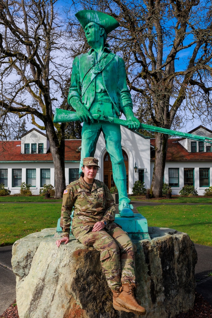 Spc. Rusha Adams, an information technology specialist with 1st Squadron, 303rd Cavalry Regiment, sits next to the Washington National Guard Minuteman Statue on Camp Murray, Wash., Feb. 26, 2025.