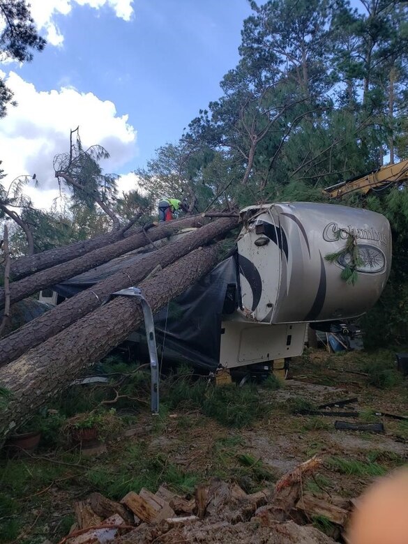Photo of a camper with fallen trees on top.