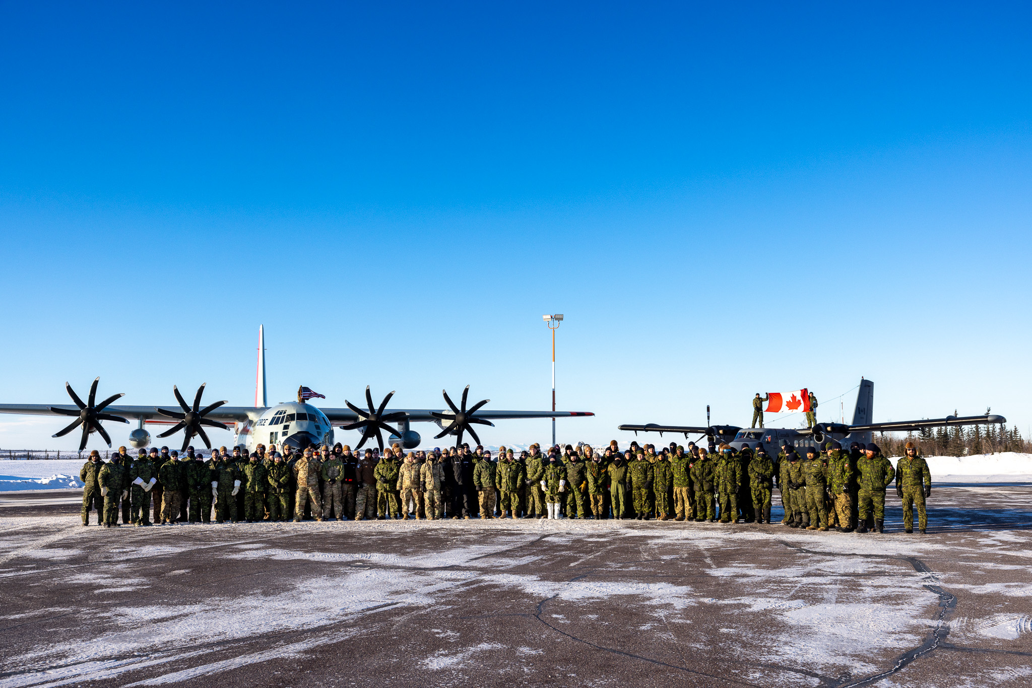 U.S. Air National Guard airmen and Canadian Forces pose for a photo in front of a LC-130 Hercules from the 109th Airlift Wing, New York Air National Guard and a CC-138 Twin Otter attached to the 440 Transport Squadron, Royal Canadian Air Force on March 7, Inuvik, Canada. The LC-130 Hercules and CC-138 Twin Otter aircraft are both able to land on snow and ice with skis. 

 (U.S. Air National Guard photo by Staff Sgt. Jocelyn Tuller)