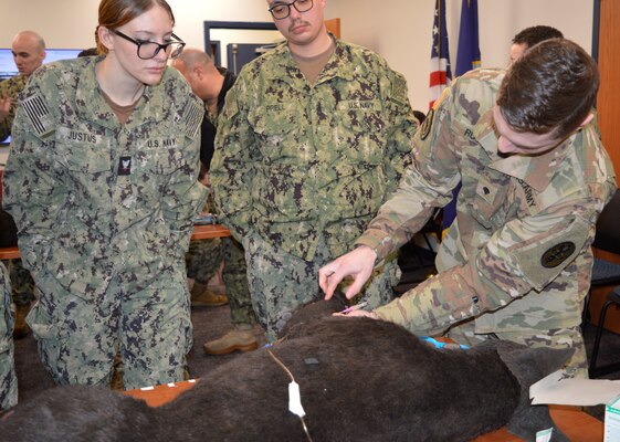 Corpsmen and Canine Collaboration…Navy hospital corpsmen, along with Navy Medical Corps, Medical Service Corps and Nurse Corps officers assigned to Navy Medicine Readiness Training Unit Bangor, augmented their Tactical Combat Casualty Care proficiency learning from U.S. Army Veterinary Corps and animal care specialist about providing battlefield trauma care to military working dogs (Official Navy photo by Douglas H Stutz, NHB/NMRTC Bremerton public affairs officer).