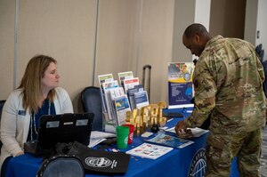 Airman grabs pamphlet from desk managed by consultant. (U.S. Air Force photo by Airman 1st Class Donnell Ramsey)
