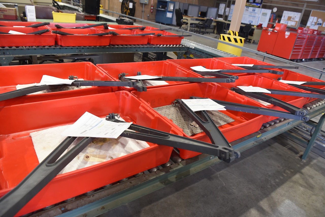 Aircraft parts in a warehouse are prepared for delivery in orange containers on an assembly line.
