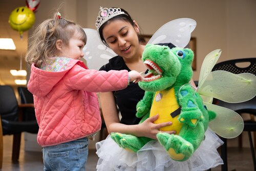 Airman 1st Class Alondra Ramos, dental technician dressed as tooth fairy kneels down to interact with little patients awaiting their appointment in the lobby.