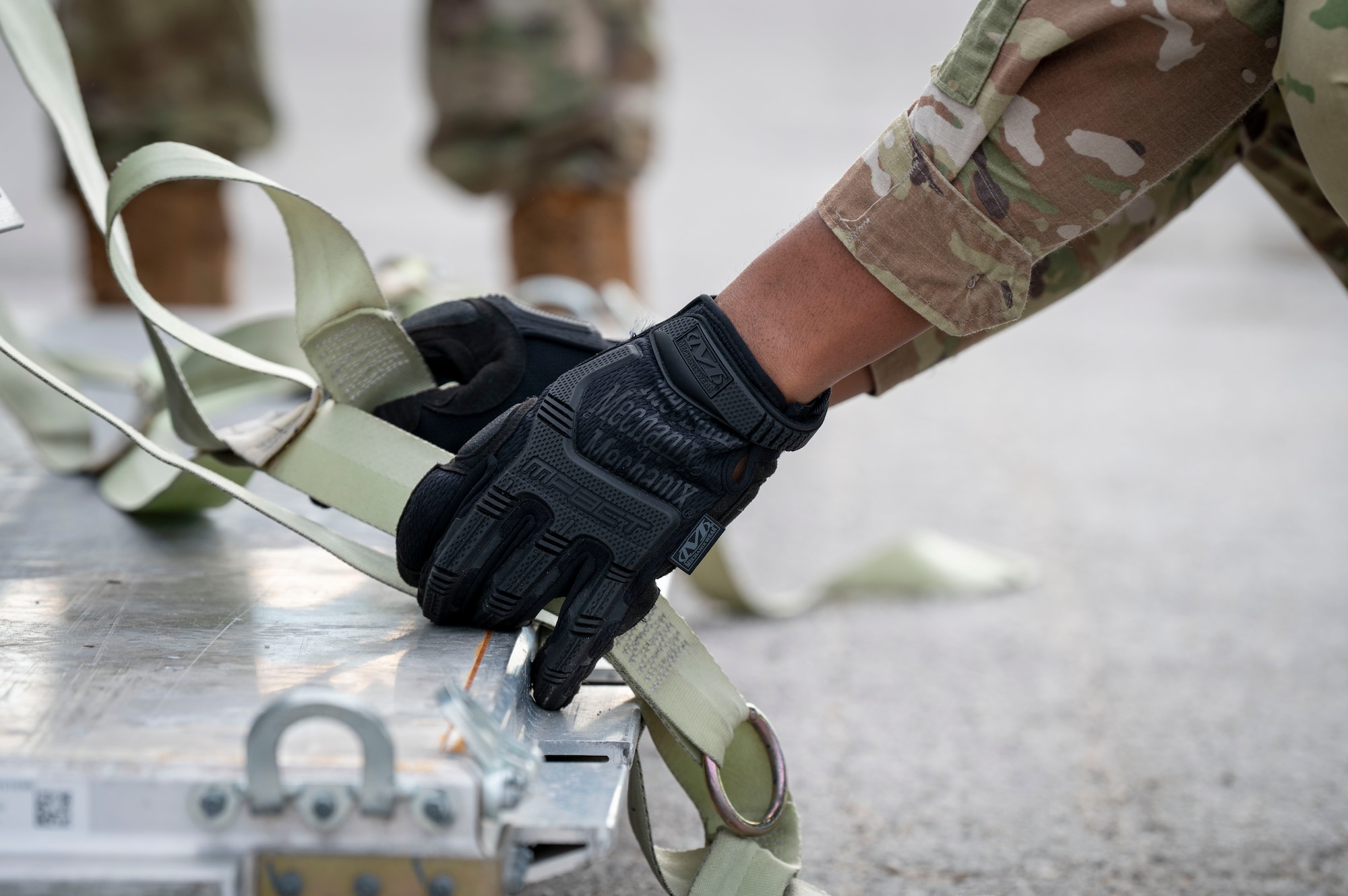 A U.S. Air Force Airman adjusts the strap on a cargo pallet during increment monitor training.