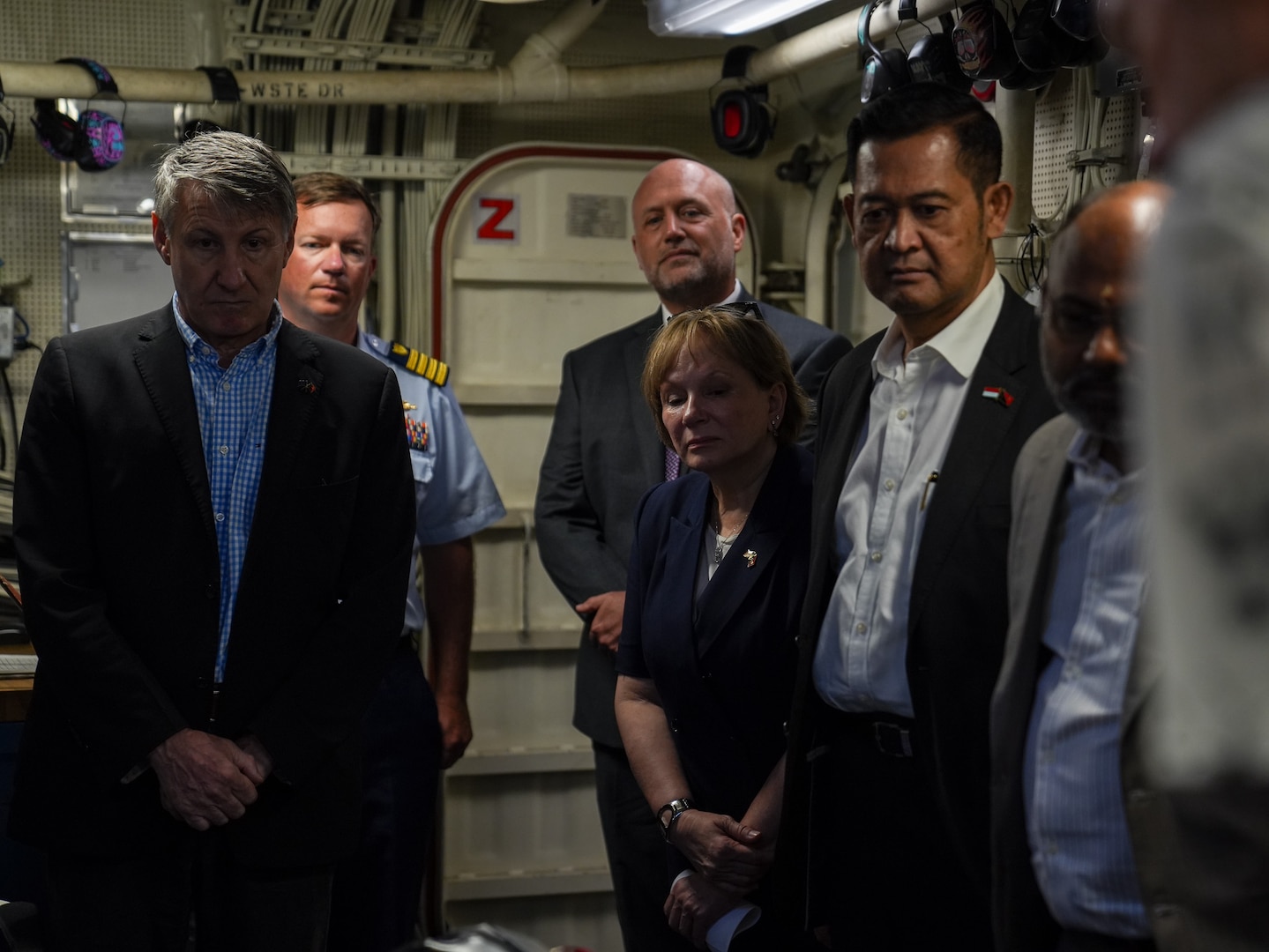 Officials from multiple agencies stand in the engine control room of the Coast Guard Cutter Midgett (WMSL 757) in Papua New Guinea Mar. 6, 2025. Papua New Guinea lies in the heart of key shipping routes, where freedom of navigation for the transport of global goods and fisheries and deep-sea resources abounds. The Coast Guard and Papua New Guinea collaborate to mitigate shared maritime challenges and threats, promoting regional security and stability within Oceania. (U.S. Coast Guard photo by Petty Officer 3rd Class Jennifer Nilson)